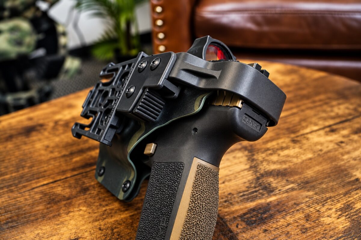 Rotating hood and thumb-lever release with Safariland QLS fork mounted on the holster back